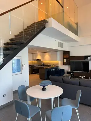 a living room with a table and blue chairs at DAMAC AMMAN LUXURY APARTMENTs داماك عمان شقق فاخرة in Amman