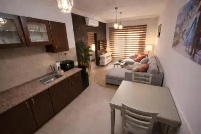 a kitchen and living room with a couch and a table at Cozy Studio Gardens St Neighborhood in Amman
