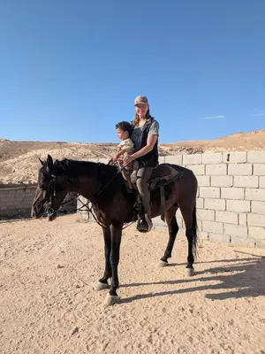 a man and a child riding on a horse at Bedouin Family Camp in Al Ḩayy