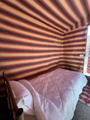 a bed in a room with a striped wall at Bedouin Family Camp in Al Ḩayy