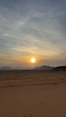 a sunset in the desert with the sun in the distance at Wadi Ram camp in Disah