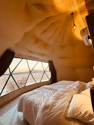 a bed in a room with a large window at Wadi Ram camp in Disah