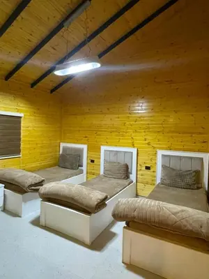 three beds in a room with a yellow wall at شاليه غصن in Ajloun