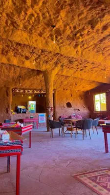 a room with tables and chairs in a cave at Amjad Rum Camp in Disah