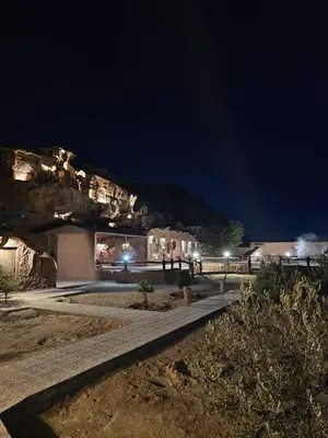 a building at night with a mountain in the background at Amjad Rum Camp in Disah