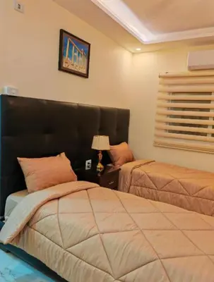 a bedroom with two beds and a table with a lamp at I cloud Petra hostel in Wadi Musa