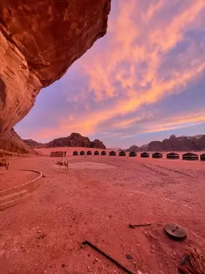 a camel walking in the desert under a bridge at Wadi Rum Heritage Camp in Wadi Rum