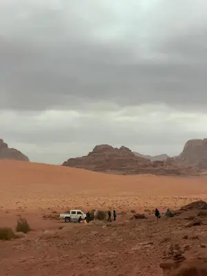 a group of people and a truck in the desert at Wadi Rum Heritage Camp in Wadi Rum