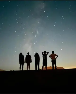 a group of people looking up at the night sky at Wadi Rum Heritage Camp in Wadi Rum