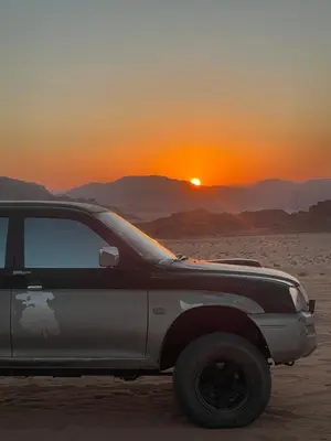 a truck parked in the desert with the sunset in the background at Wadi Rum Heritage Camp in Wadi Rum