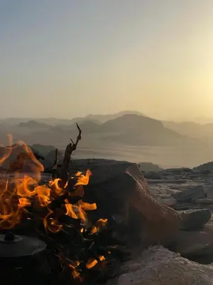 a campfire on the rocks with the mountains in the background at Wadi Rum Heritage Camp in Wadi Rum