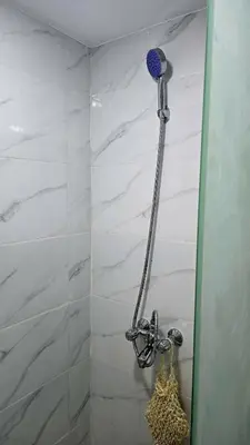 a shower with a blue shower head in a bathroom at Tariq Camp Wadi Rum in Wadi Rum