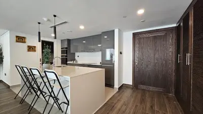 a kitchen with a island and a counter with chairs at Luxury 2-BR Apartment Abdali Boulevard Family in Al Jafr