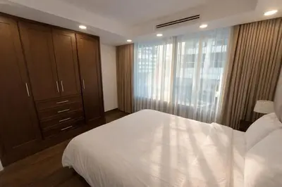 a bedroom with a large white bed and a window at Gampbell Gray Elite Abdali Apartment in Amman