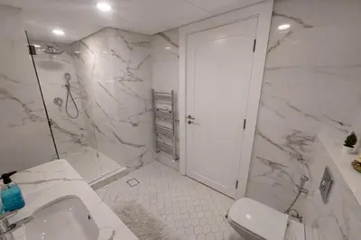 a white bathroom with a shower and a sink at Gampbell Gray Elite Abdali Apartment in Amman