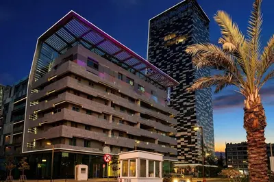 a tall building with a palm tree in front of it at Gampbell Gray Elite Abdali Apartment in Amman