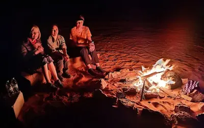 a group of people sitting around a fire at Wadi Rum Tours and Camp in Wadi Rum