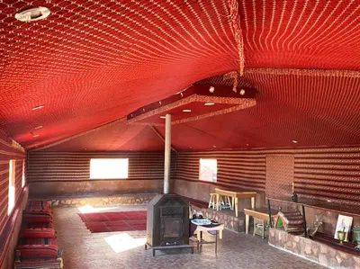 a large room with a fireplace and tables and chairs at Wadi Rum Tours and Camp in Wadi Rum