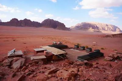 a building in the middle of a desert with mountains at Wadi Rum Tours and Camp in Wadi Rum