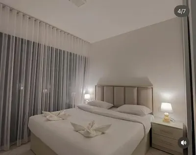a bedroom with a large bed with two flowers on it at Seaside Luxury Apartment with Terrace and BBQ in Aqaba