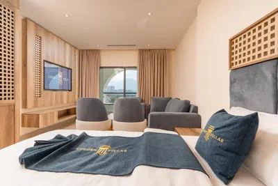 a hotel room with a bed with chairs and a television at Golden Pillar Hotel in Aqaba