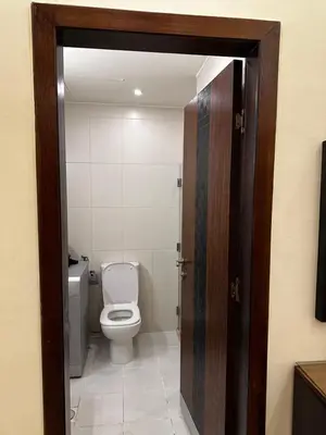 a bathroom with a toilet and a wooden door at شقة بالرابية in Amman