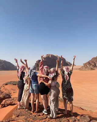 a group of people standing on a rock in the desert at BUBBLES CAMp in Wadi Rum