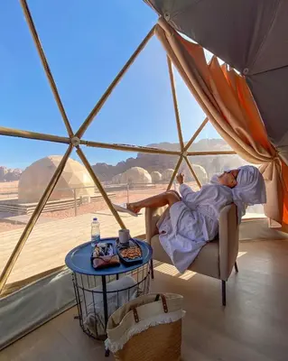 a woman laying on a chair in a tent at BUBBLES CAMp in Wadi Rum