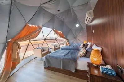 a bedroom in a tent with a bed and a table at Desert Stars Bubble Camp Wadi Rum in Wadi Rum