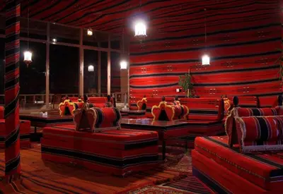 a room with red chairs and tables in a building at Rocky Mountain Hotel Jordan in Petra
