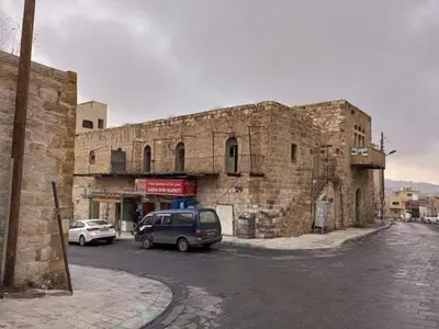 a stone building with cars parked in front of it at Kirakoupdolis house & restaurant in Kerak