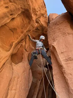 a woman is climbing on a rock formation at Aseel camp rum in Wadi Rum