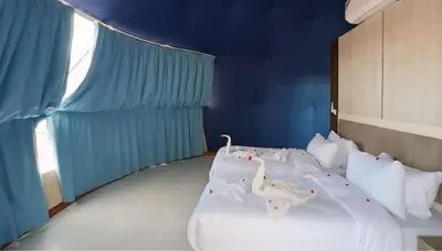 a bedroom with white beds with blue walls and a window at Aseel camp rum in Wadi Rum