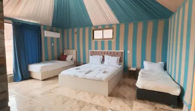 two beds in a room with striped walls at Aseel camp rum in Wadi Rum