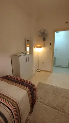 a bedroom with a bed and a room with a fan at حي الجامعة خلف الجامعة الاردنية in Amman