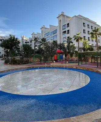 a large circular pool in front of a large building at Luxury apartment for rent in BoulevardAirport Road in Amman