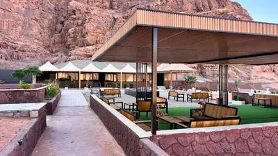 a building with benches and tables in front of a mountain at Wadi Rum Desert Memory in Wadi Rum