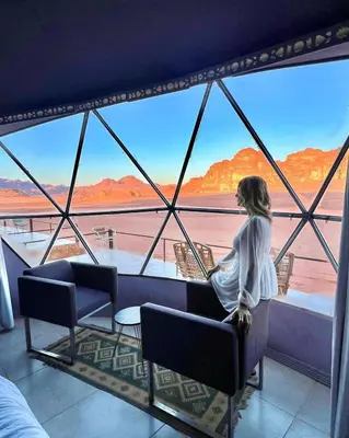 a woman sitting in a chair in a room with a view at Bubble's Home in Wadi Rum
