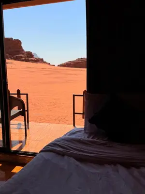 a bed in a room with a view of the desert at Desert Moon Camp in Wadi Rum