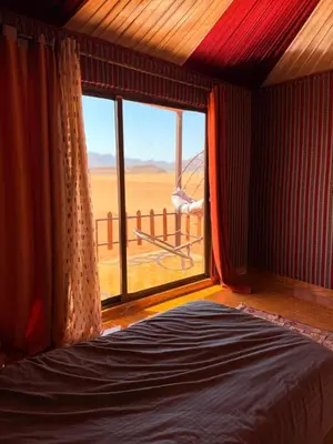 a bedroom with a bed and a large window at Desert Moon Camp in Wadi Rum