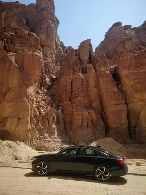 a black car parked in front of a mountain at سياره ليموزين in Amman
