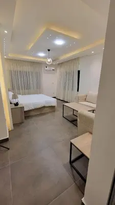 a bedroom with a bed and a couch and tables at Lavender Résidence 102 in Amman