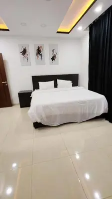 a bedroom with a large white bed with black curtains at La Perla Apertment Family in Amman