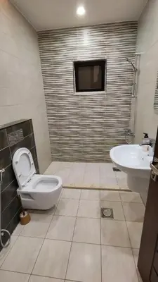 a bathroom with a toilet and a sink and a tv at La Perla Apertment Family in Amman