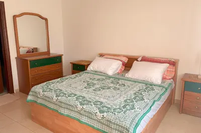 a bedroom with a bed with a dresser and a mirror at Comfy Apt at Jandawil -only Families- in Amman