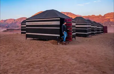 a man standing inside a row of tents in the desert at Wadi Rum Moon Light in Wadi Rum