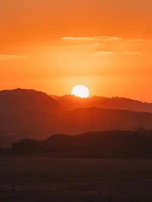 a sunset in the desert with the sun in the sky at Wadi Rum Moon Light in Wadi Rum