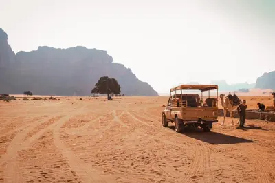 a truck parked in the desert with a camel at Rum Cave Tours in Wadi Rum