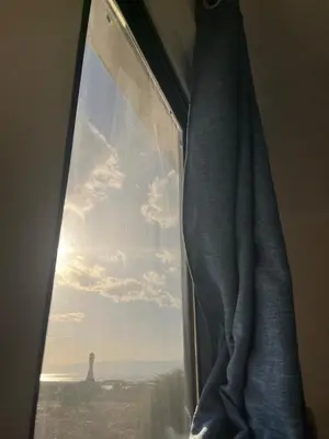a window with a view of a lighthouse at الحمد للاجنحة الفندقية in Aqaba