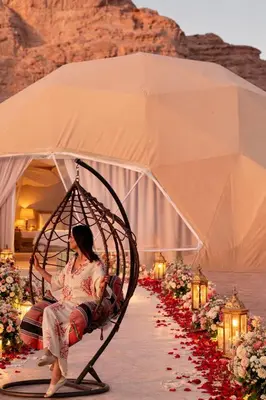 a woman sitting in a swing in front of a tent at wadi rum Bubble lunara luxury camp in Wadi Rum